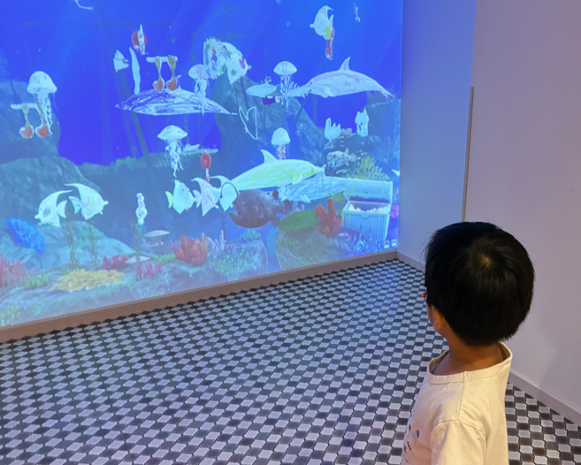 ホテルニューアカオキッズパークのデジタル水族館で魚に触れる子ど