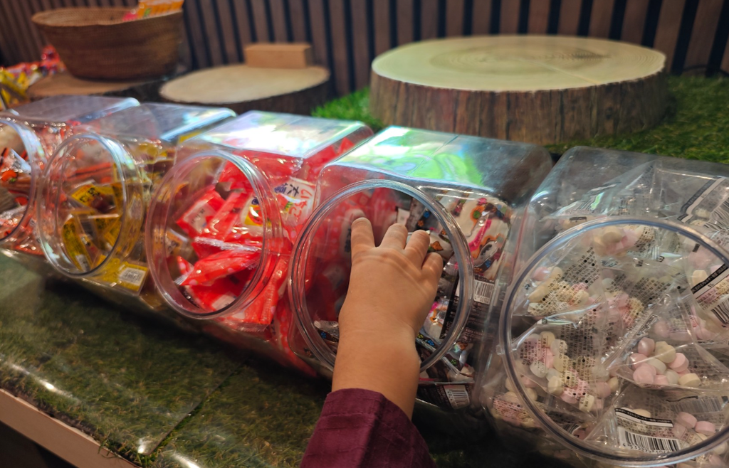 駄菓子コーナーのお菓子を取る子どもの手