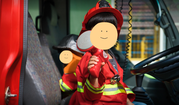 消防車の運転席で消防士の衣装を着た子ども